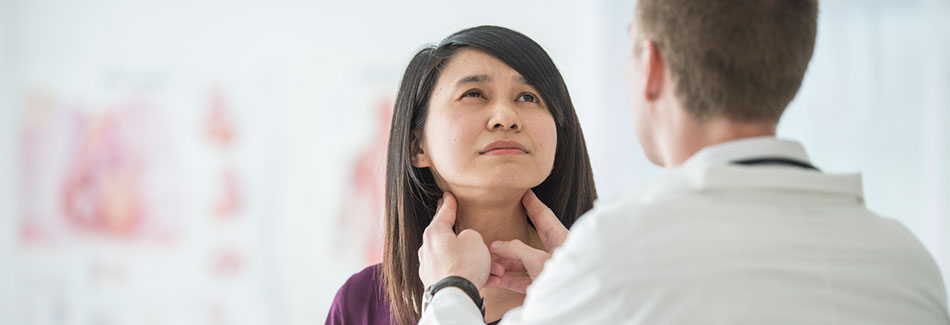 Doctor performing a screening on a female patient for symptoms of thyroid cancer.