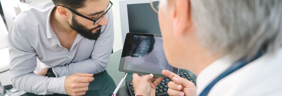 Male doctor using a digital tablet to show a patient his lung cancer diagnosis.